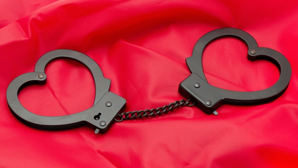 heart shaped handcuffs on a red satin background