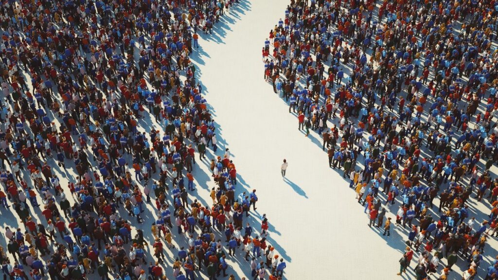 Person walks alone on a path between two largely populated crowds