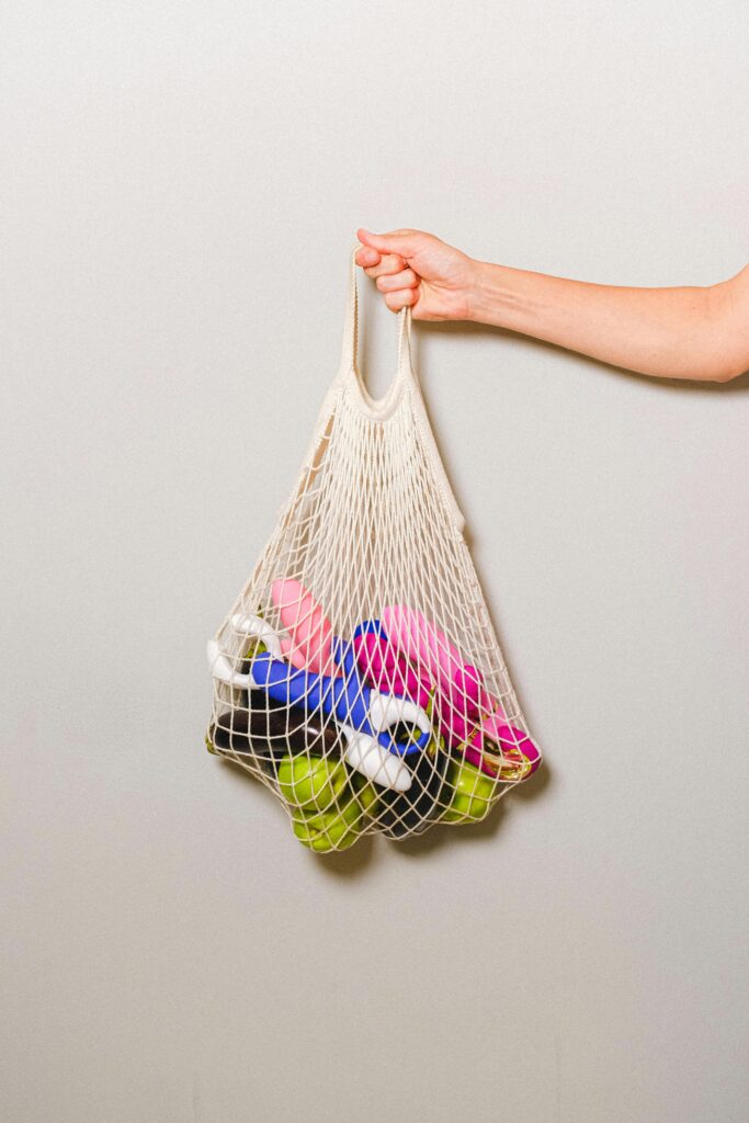 a collection of sex toys in a net being held up by a hand