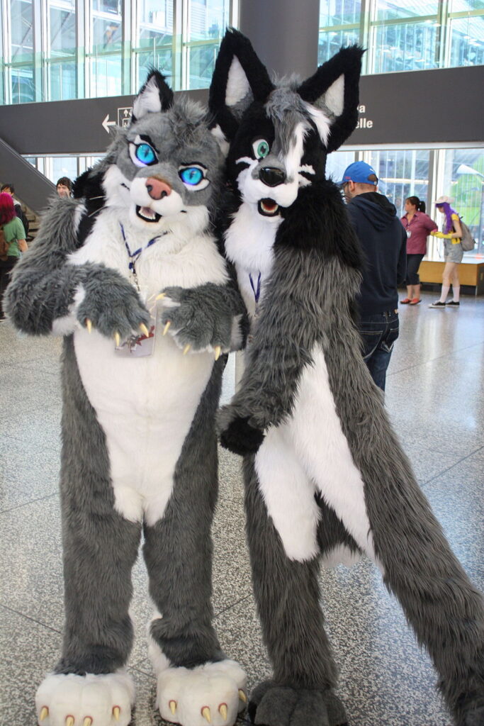 Two people dressed in full furry costumes at a furry convention. 