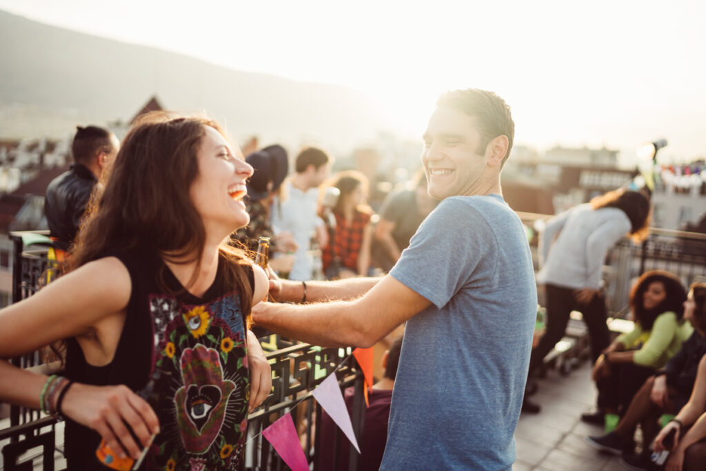 Two friends laughing together on a rooftop terrace.