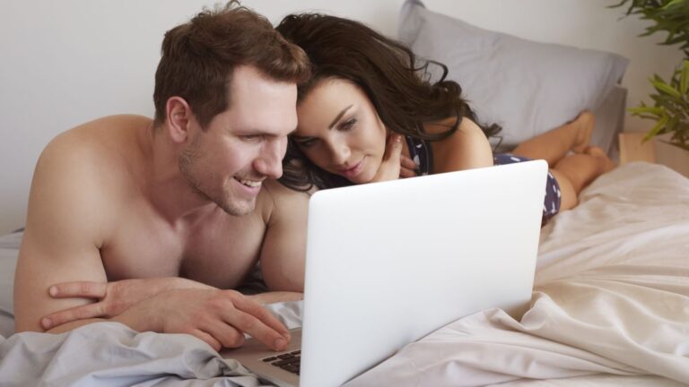 Couple on bed watching laptop