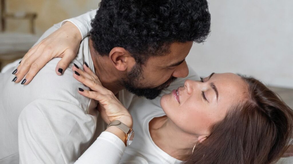 multiethinic couple wearing white lying down about to kiss