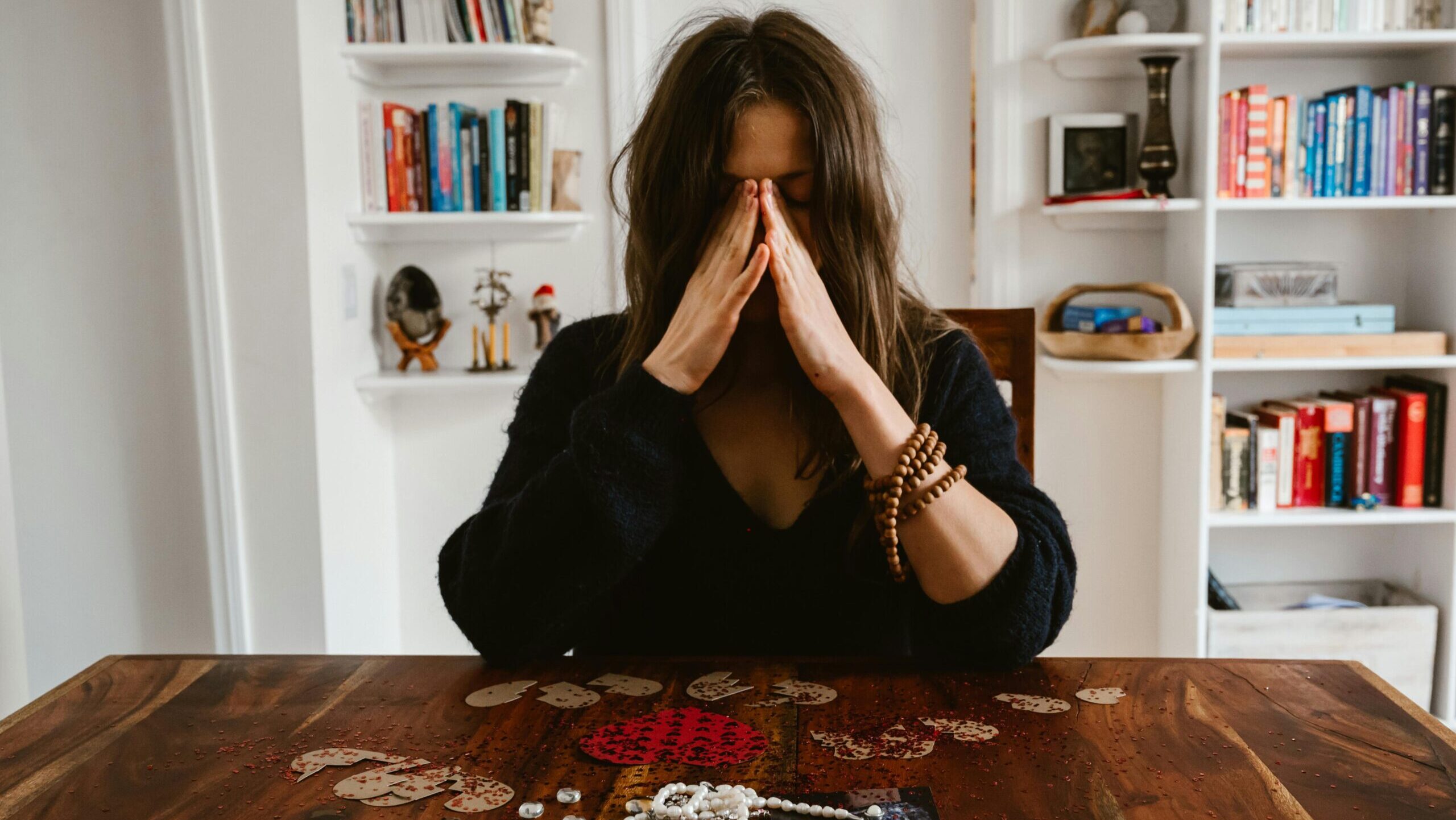 women sitting at her table looking stressed with head in her hands.